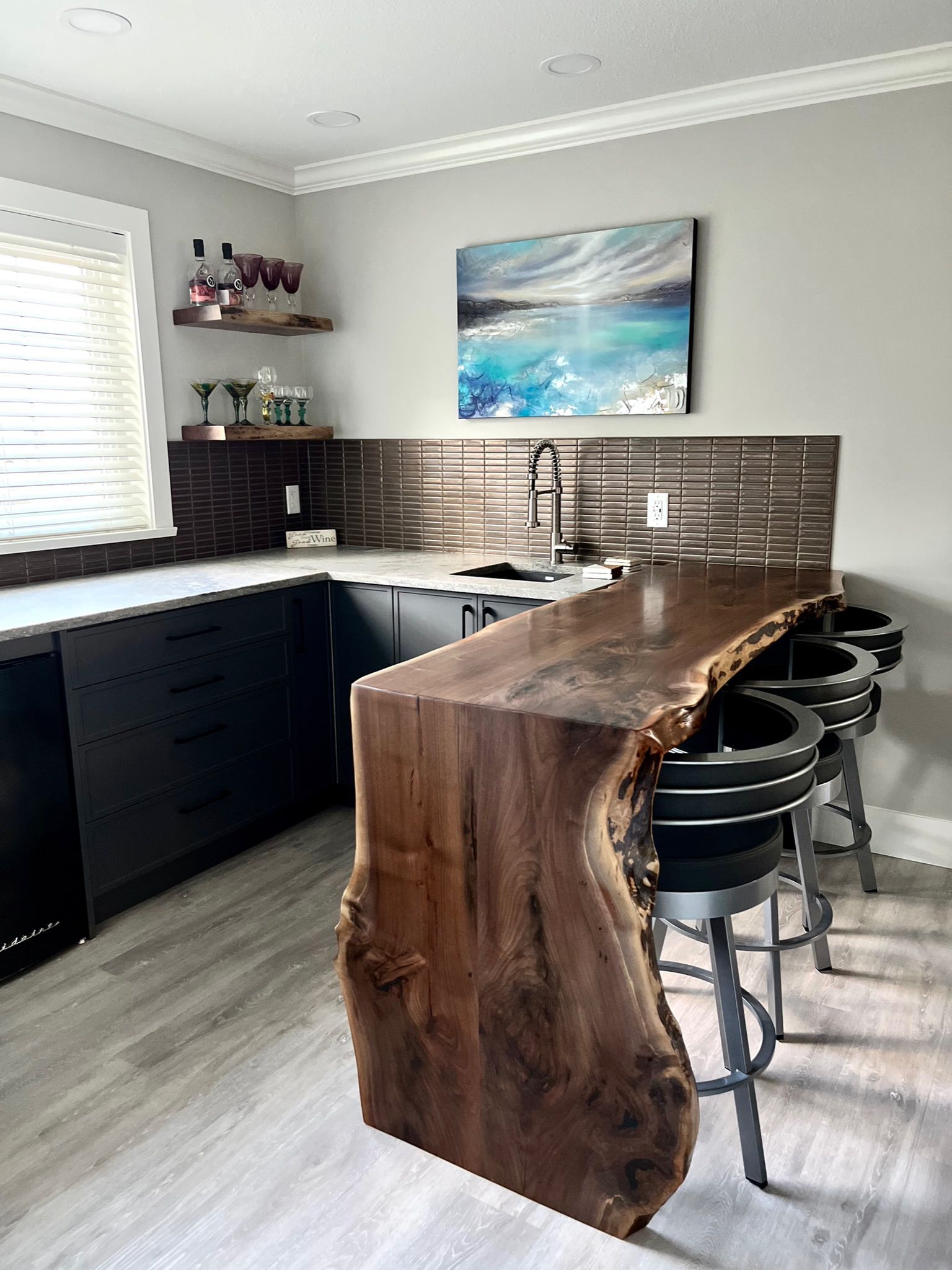 Dark navy kitchen with live-edge walnut bar top, bronze tile backsplash and bar stools